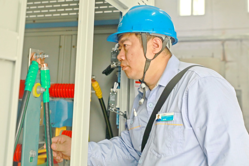 图为：仪电中心电气技术员陈双军查看配电柜接线图
