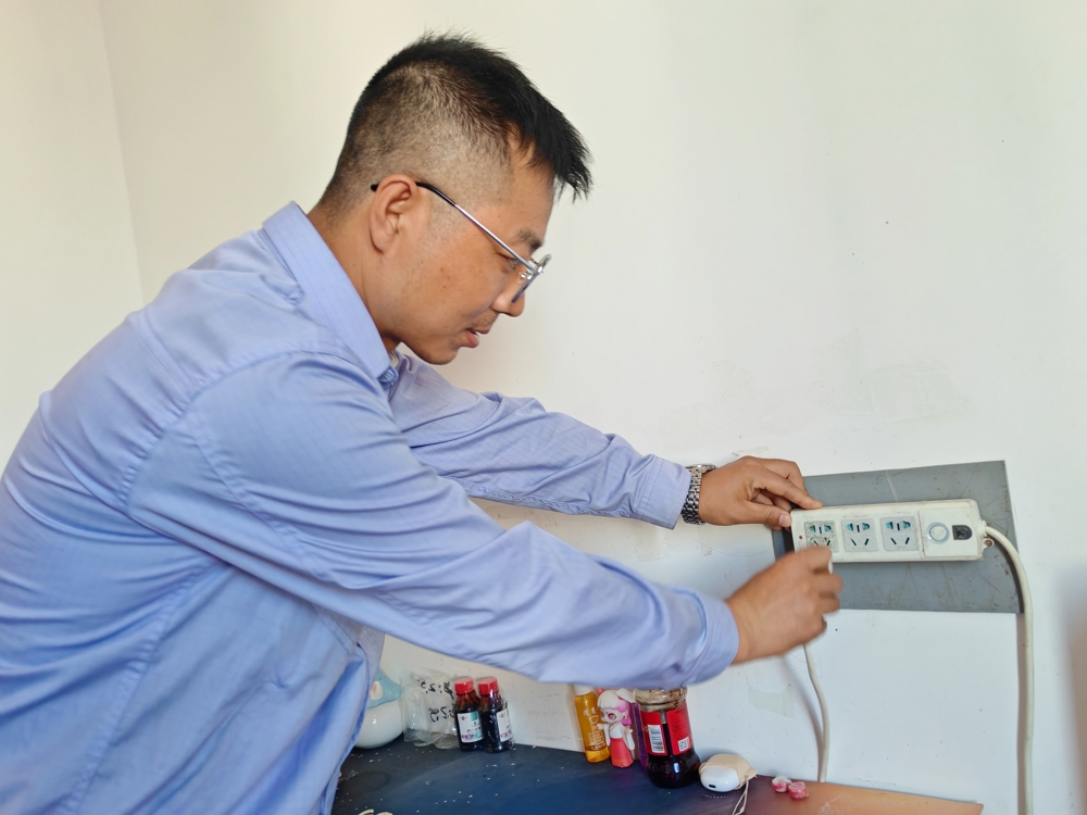图为专业技术人员正在职工宿舍检查插线板使用情况。